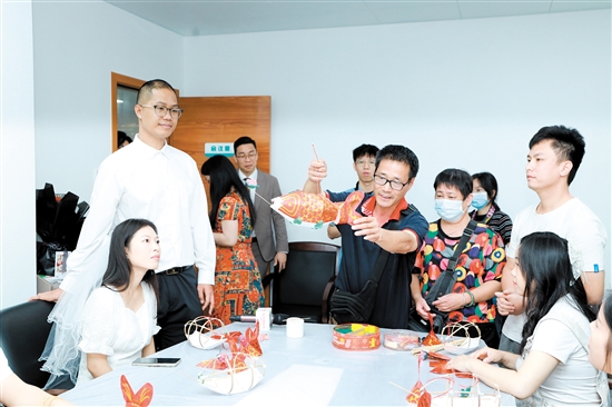 昨日，在新會區(qū)民政局婚姻登記處，工作人員向剛領(lǐng)證的新人們展示新會魚燈制作技巧。