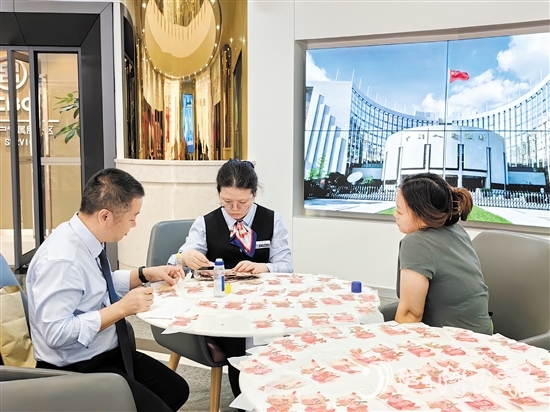 工行江門分行營(yíng)業(yè)部工作人員為客戶鑒別殘幣。
