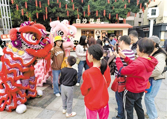 游客在長(zhǎng)堤歷史文化街區(qū)與醒獅合影。何雯意