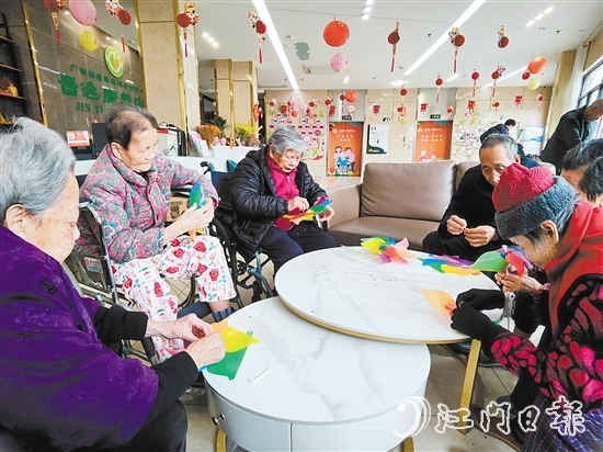 老人們圍坐在桌前，專注地制作小風(fēng)車(chē)。