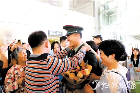 身著軍裝的返鄉(xiāng)退役士兵逐一出站，迎接他們的是鮮花與擁抱。