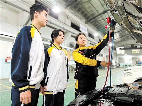 黃錚（右一）在汽修實(shí)訓(xùn)車(chē)間指導(dǎo)學(xué)生。