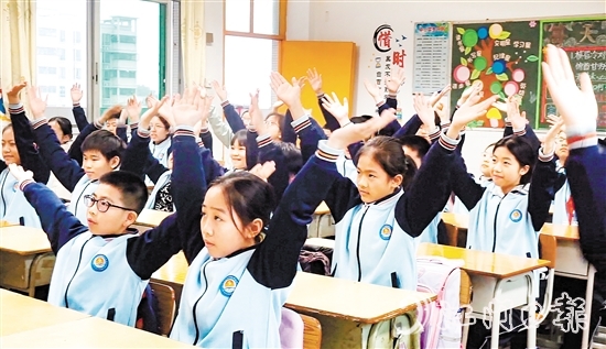 學(xué)生們?cè)谡n桌前跟隨節(jié)奏做起“室內(nèi)課桌操”。