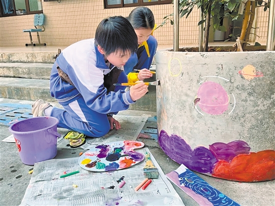 學(xué)生們在校園內(nèi)的花墩上進(jìn)行精心繪制，為校園風(fēng)景增色添彩。