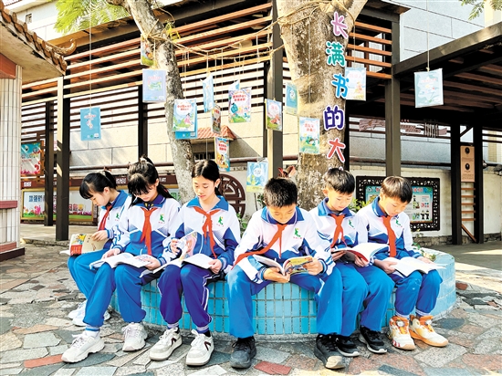 龍口鎮(zhèn)協(xié)華小學(xué)學(xué)生圍坐在“長滿書的大樹”下捧書共讀，成為該校一道亮麗的風(fēng)景線。