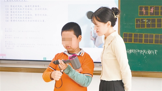 小明在老師指導(dǎo)下學(xué)習(xí)使用吹風(fēng)機(jī)。