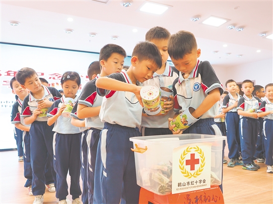 學(xué)生代表將愛(ài)心儲(chǔ)蓄罐里的零錢(qián)投入捐款箱，匯聚點(diǎn)滴愛(ài)心。