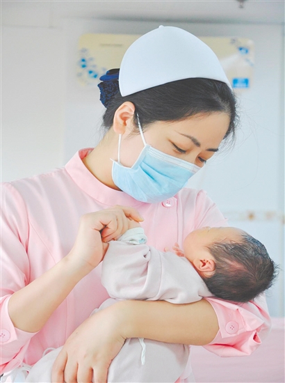 這是一雙托起生命的手。江門市中心醫(yī)院愛嬰?yún)^(qū)主管護(hù)師湯玲玲正在安撫哭鬧的寶寶。她一手環(huán)住襁褓，一手牽起寶寶的小手，動作舒緩而溫柔。在這里，生命的啼哭與溫柔的守護(hù)相遇，匯聚成世間至暖的力量。（林錦棠