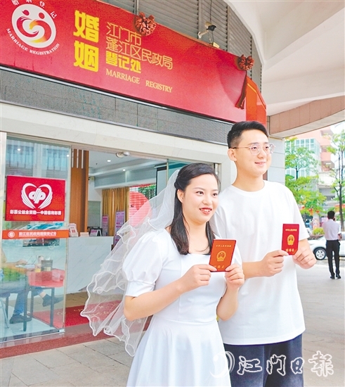 一對(duì)新人在蓬江區(qū)民政局婚姻登記處門口合影留念。