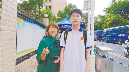 身著綠色旗袍的李女士與兒子合影。