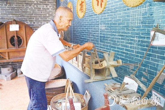 新華村打造農(nóng)耕文化展館，留住鄉(xiāng)村記憶。圖為村中老人向記者介紹農(nóng)具。