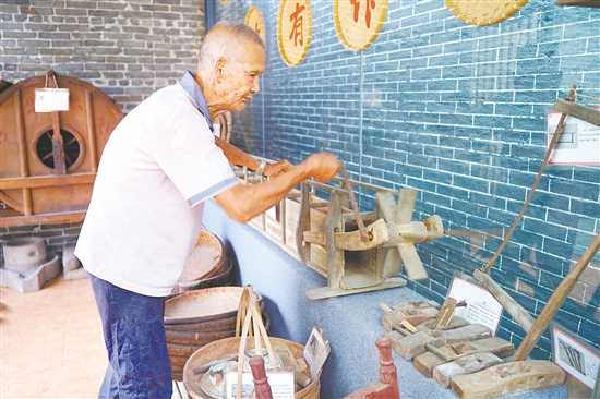 新華村打造農(nóng)耕文化展館，留住鄉(xiāng)村記憶。圖為村中老人向記者介紹農(nóng)具。