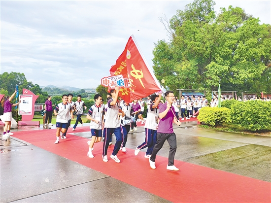 在臺(tái)山市武溪中學(xué)，老師揮舞著“中考加油”的紅旗為考生加油助威。