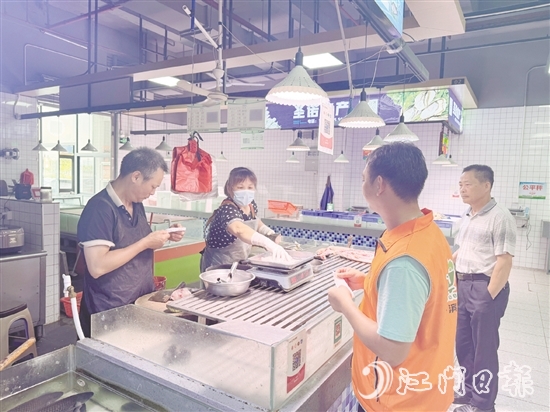 買(mǎi)菜易的平臺(tái)接單員李叔（橙色馬甲）正在魚(yú)攤旁等待取單。