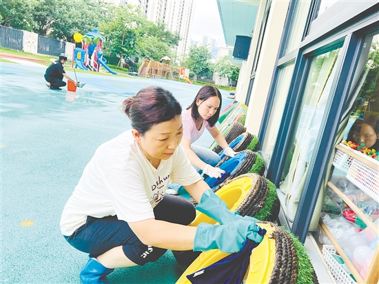 蓬江區(qū)實(shí)驗(yàn)幼兒園的老師們把教學(xué)道具輪胎放在避雨處，并清理積水。