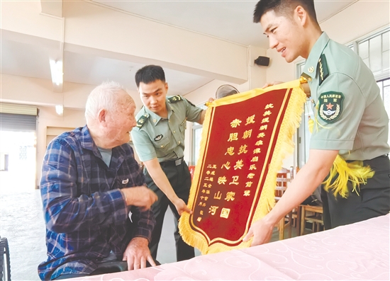 部隊(duì)官兵代表向譚啟樂(lè)送上錦旗。