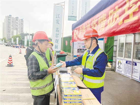 工地施工人員排隊領(lǐng)取防蚊用品。