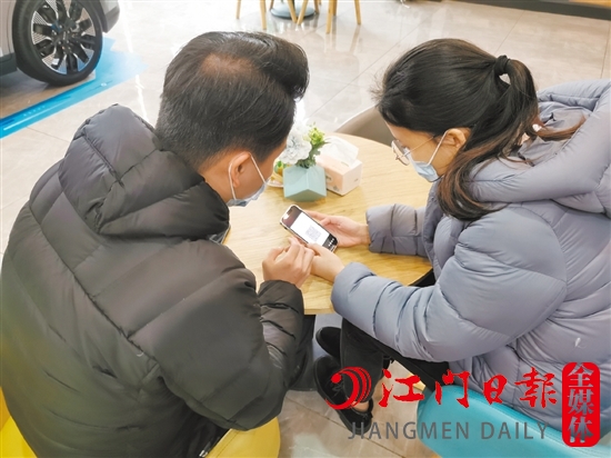 新能源汽車銷售人員協(xié)助車主用手機(jī)進(jìn)行投保新能源汽車險。
